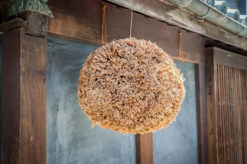 A cedar ball, the traditional sign of a sake brewery, hanging from wooden eaves