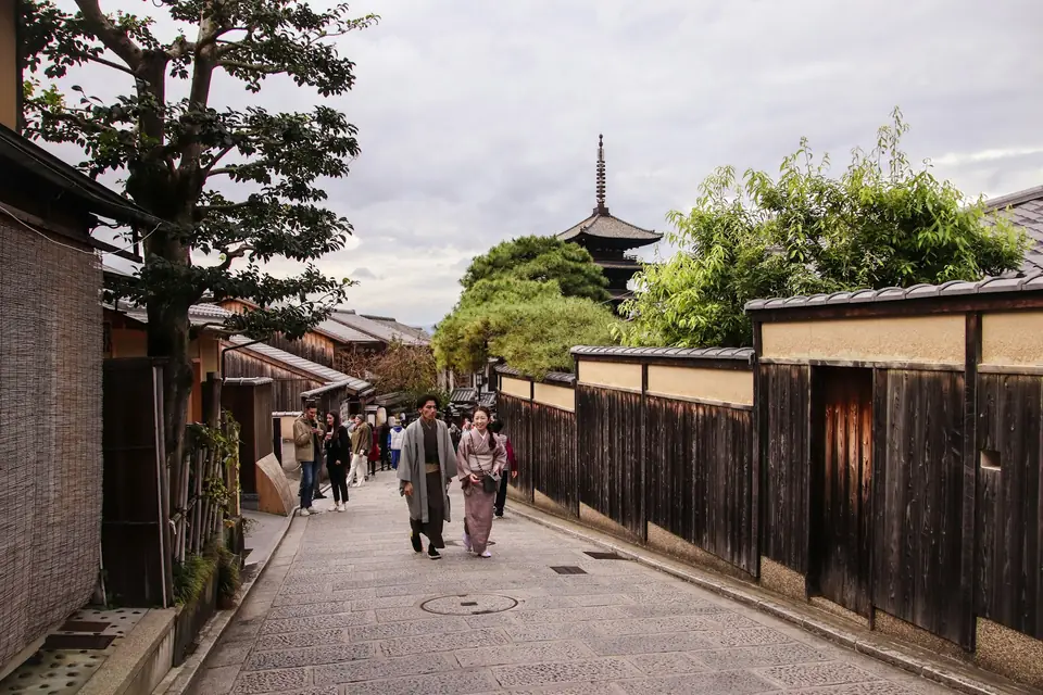 Travelers walking a traditional lane in Higashiyama with a pagoda beyond