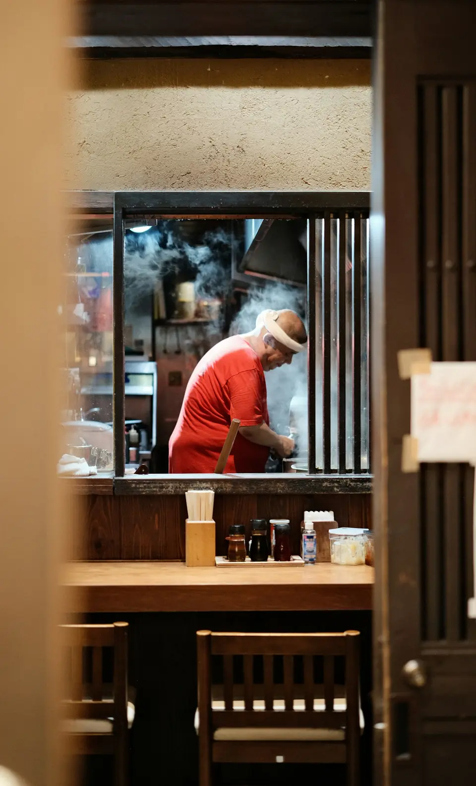 A cook working over a steaming counter kitchen